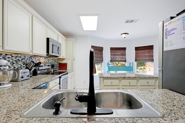 7410 Tom Watson, San Antonio, TX 78244 - kitchen featuring stainless steel appliances, a sink, tasteful backsplash, white cabinetry, and light stone countertops