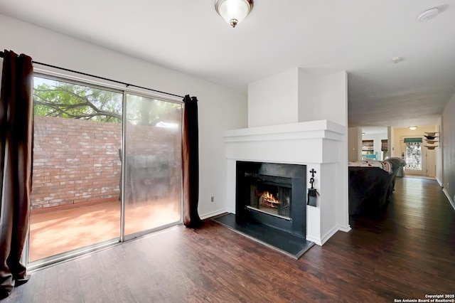 7410 Tom Watson, San Antonio, TX 78244 - unfurnished living room featuring dark wood finished floors and a warm lit fireplace