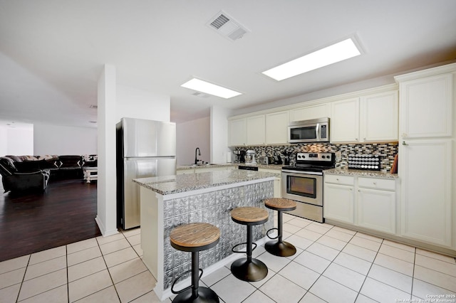 7410 Tom Watson, San Antonio, TX 78244 - kitchen with stainless steel appliances, light tile patterned flooring, a sink, backsplash, and light stone counters