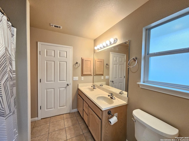 2115 Bentwood, New Braunfels, TX 78130 - full bath with double vanity, tile patterned flooring, toilet, a textured ceiling, and baseboards