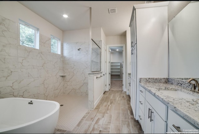 8119 Ventura Blvd, Selma, TX 78154 - full bathroom with a marble finish shower, vanity, a freestanding tub, a walk in closet, and wood finish floors