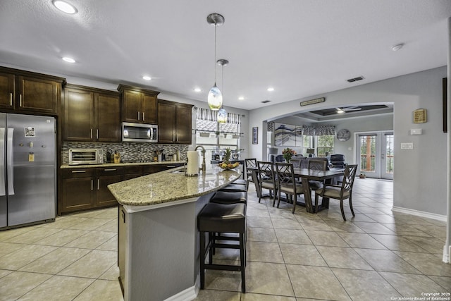 18131 Muir Glen Dr, San Antonio, TX 78257 - kitchen featuring stainless steel appliances, backsplash, light stone counters, light tile patterned floors, and recessed lighting
