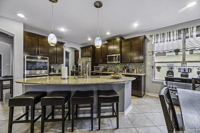 18131 Muir Glen Dr, San Antonio, TX 78257 - kitchen featuring appliances with stainless steel finishes, a sink, tasteful backsplash, a breakfast bar area, and dark brown cabinets
