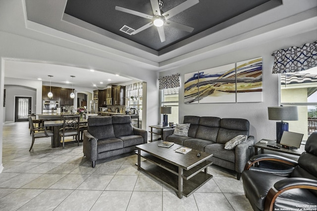 18131 Muir Glen Dr, San Antonio, TX 78257 - living area with arched walkways, a tray ceiling, light tile patterned floors, ceiling fan, and plenty of natural light