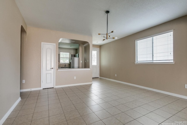 1023 Sundance Fall, San Antonio, TX 78245 - unfurnished room with a chandelier, baseboards, light tile patterned flooring, and arched walkways