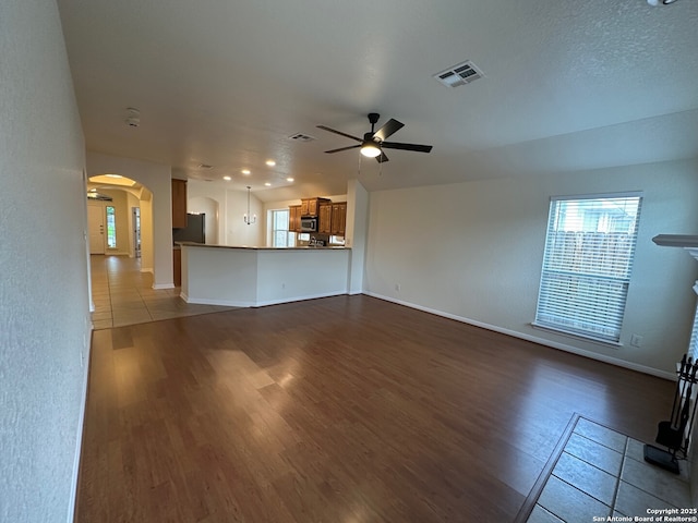 520 Ginsberg, Schertz, TX 78154 - unfurnished living room featuring arched walkways, a ceiling fan, wood finished floors, and baseboards
