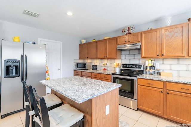 11807 Amber Tree, San Antonio, TX 78254 - kitchen featuring appliances with stainless steel finishes, under cabinet range hood, light tile patterned flooring, a center island, and decorative backsplash
