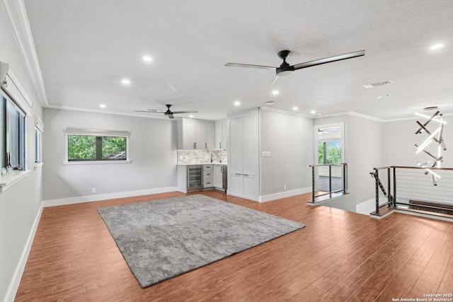 3902 Creek Pt, San Antonio, TX 78230 - unfurnished living room featuring beverage cooler, a ceiling fan, recessed lighting, ornamental molding, and healthy amount of natural light