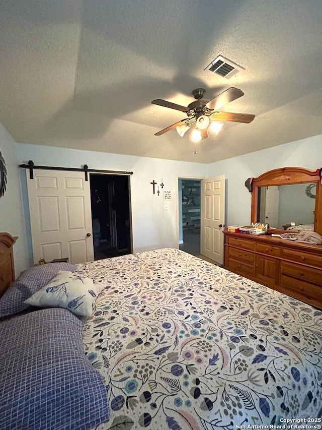 129 W High Line, Trinity, TX 75862 - bedroom with a barn door, a textured ceiling, and ceiling fan