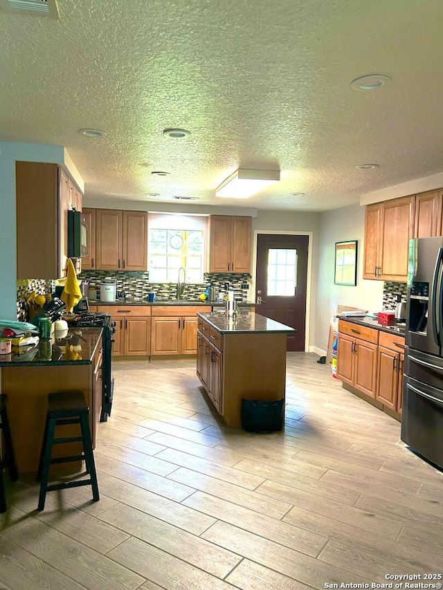 129 W High Line, Trinity, TX 75862 - kitchen with refrigerator with ice dispenser, black gas range oven, a sink, light wood-style floors, and a textured ceiling