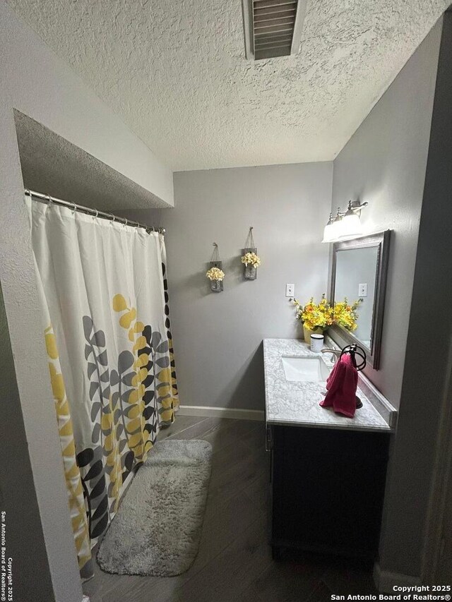 129 W High Line, Trinity, TX 75862 - bathroom with vanity, wood finished floors, baseboards, a textured ceiling, and a shower with shower curtain
