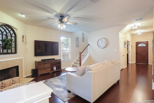 17206 Ashbury, San Antonio, TX 78247 - living room with ceiling fan, a tiled fireplace, dark wood-style floors, stairs, and baseboards