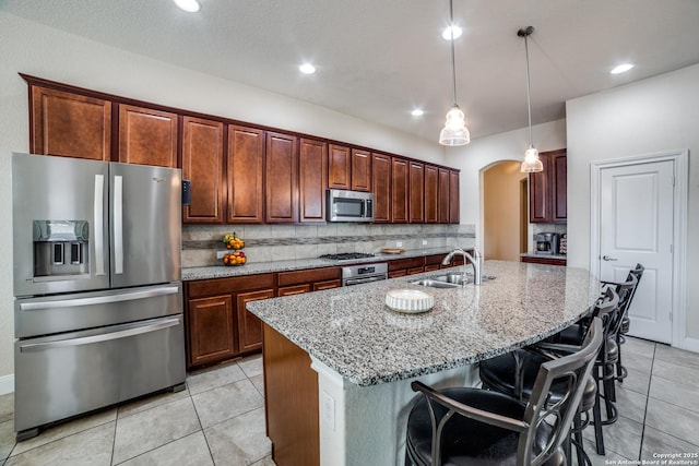 2023 Wilby Ln, San Antonio, TX 78253 - kitchen with appliances with stainless steel finishes, a sink, arched walkways, light stone countertops, and tasteful backsplash