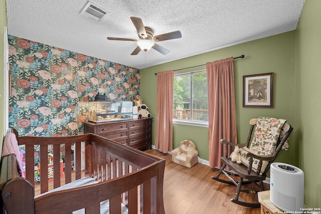 4303 Lakebend W, San Antonio, TX 78244 - bedroom with wallpapered walls, wood finished floors, a textured ceiling, baseboards, and an accent wall