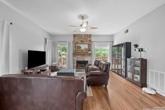 4303 Lakebend W, San Antonio, TX 78244 - living room featuring a ceiling fan, wood finished floors, a textured ceiling, and a brick fireplace