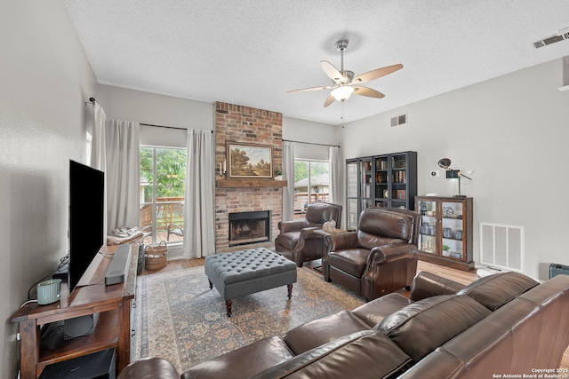 4303 Lakebend W, San Antonio, TX 78244 - living room with a ceiling fan, a textured ceiling, healthy amount of natural light, wood finished floors, and a brick fireplace