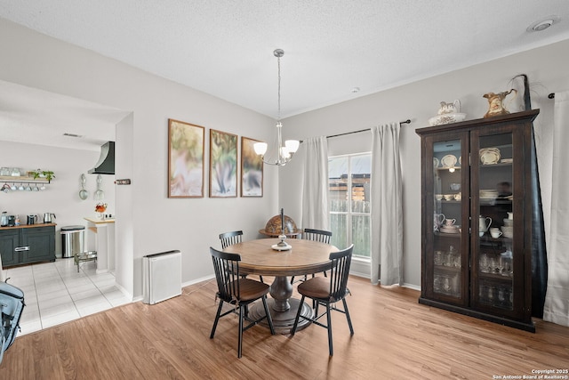4303 Lakebend W, San Antonio, TX 78244 - dining room with a chandelier, light wood-style flooring, baseboards, and a textured ceiling