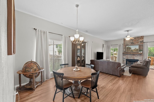 4303 Lakebend W, San Antonio, TX 78244 - dining room featuring light wood-type flooring, a brick fireplace, a ceiling fan, a chandelier, and baseboards