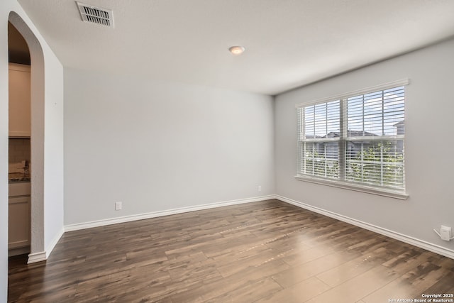 4823 Swing Arc, San Antonio, TX 78261 - spare room featuring arched walkways, dark wood finished floors, and baseboards