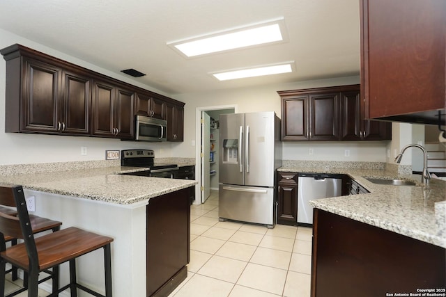 9011 Twincreek Farm, Converse, TX 78109 - kitchen with stainless steel appliances, a sink, a peninsula, light tile patterned floors, and a kitchen bar