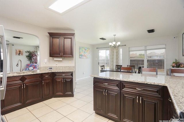 9011 Twincreek Farm, Converse, TX 78109 - kitchen with a chandelier, arched walkways, light tile patterned floors, a peninsula, and a sink