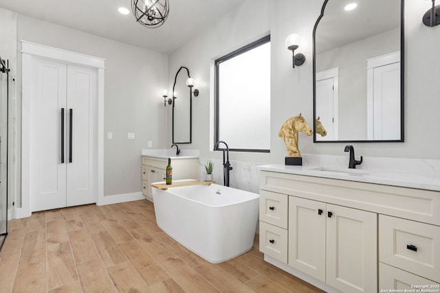 1475 Echo Mdw, Spring Branch, TX 78070 - bathroom with two vanities, a soaking tub, wood finished floors, recessed lighting, and baseboards