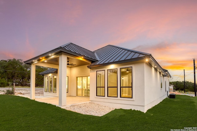 1475 Echo Mdw, Spring Branch, TX 78070 - back of house at dusk featuring a standing seam roof, ceiling fan, a lawn, metal roof, and a patio area