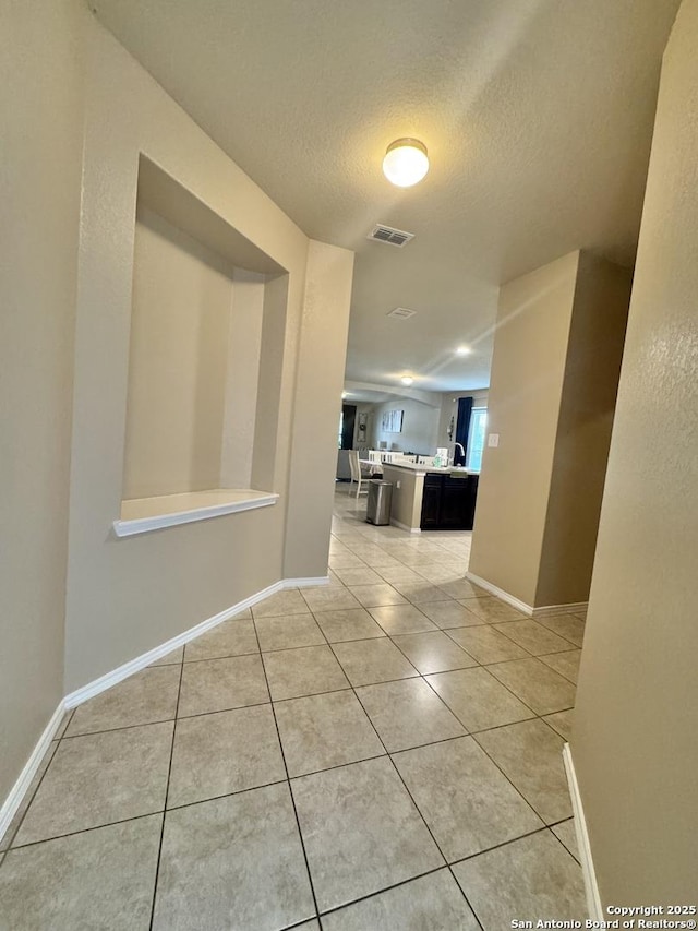 5726 Ivans Farm, San Antonio, TX 78244 - hallway with light tile patterned flooring, a textured ceiling, and baseboards