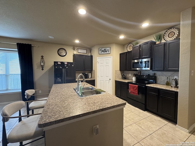 5726 Ivans Farm, San Antonio, TX 78244 - kitchen featuring black appliances, a sink, backsplash, light tile patterned floors, and a center island with sink