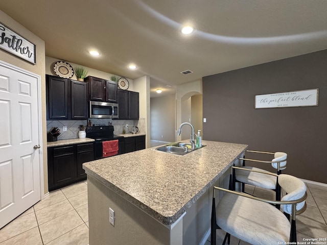 5726 Ivans Farm, San Antonio, TX 78244 - kitchen with a sink, black electric range, stainless steel microwave, light tile patterned floors, and tasteful backsplash