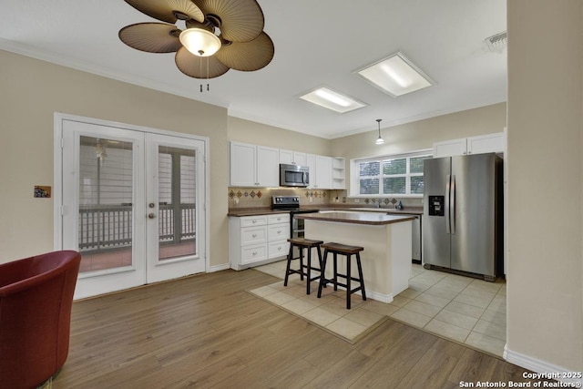 141 Rio Grande, Seguin, TX 78155 - kitchen featuring appliances with stainless steel finishes, french doors, dark countertops, white cabinets, and a breakfast bar