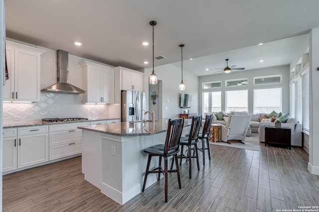 22806 Rio Salado, San Antonio, TX 78261 - kitchen featuring wall chimney exhaust hood, stainless steel appliances, a ceiling fan, backsplash, and wood finished floors