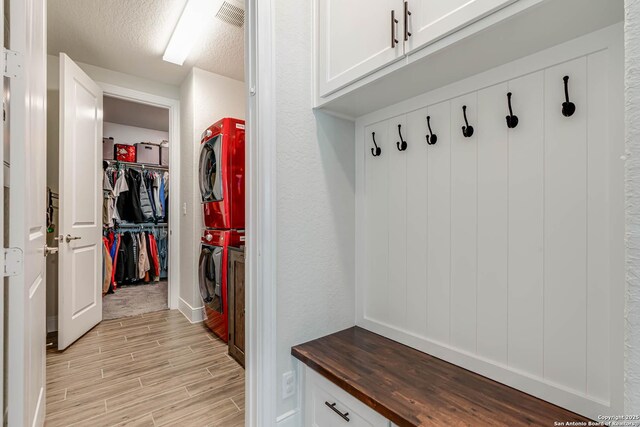 22806 Rio Salado, San Antonio, TX 78261 - mudroom with stacked washer / drying machine, light wood-style flooring, and a textured ceiling