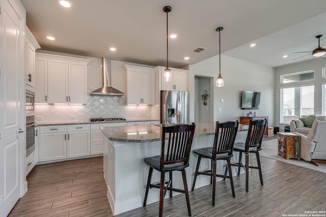 22806 Rio Salado, San Antonio, TX 78261 - kitchen featuring stainless steel appliances, wall chimney exhaust hood, open floor plan, wood finished floors, and backsplash