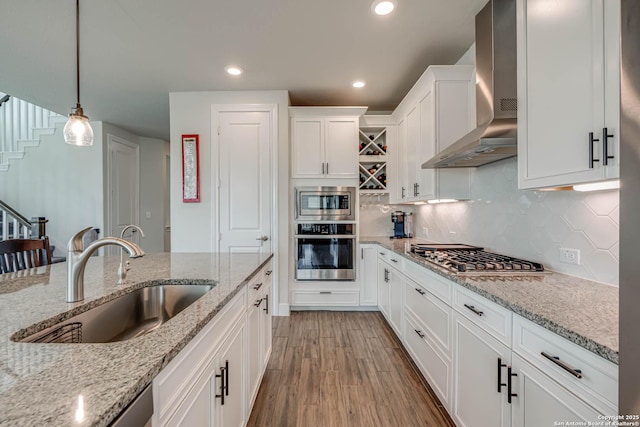 22806 Rio Salado, San Antonio, TX 78261 - kitchen featuring appliances with stainless steel finishes, wall chimney exhaust hood, white cabinetry, light wood-style floors, and decorative light fixtures