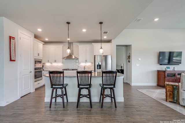 22806 Rio Salado, San Antonio, TX 78261 - kitchen featuring appliances with stainless steel finishes, white cabinets, wood finished floors, tasteful backsplash, and an island with sink