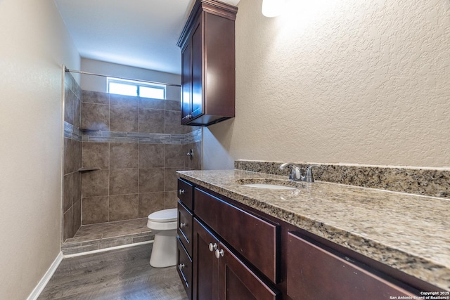 3613 Candleridge, San Antonio, TX 78244 - bathroom featuring toilet, vanity, tiled shower, wood finished floors, and a textured wall