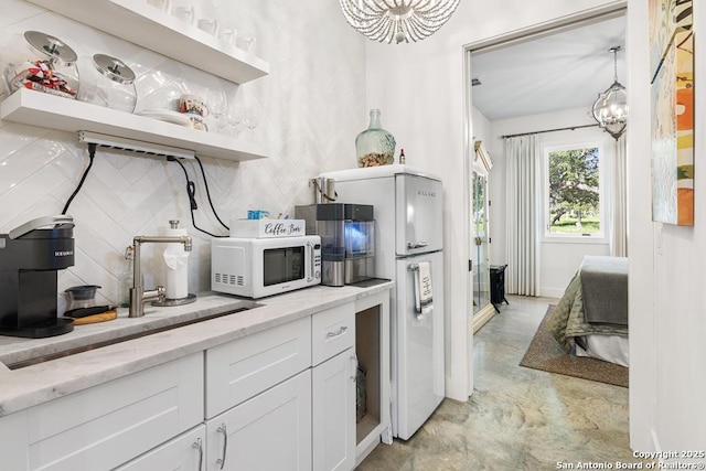 159 Inspiration, Fredericksburg, TX 78624 - kitchen featuring white appliances, decorative backsplash, white cabinets, and a chandelier