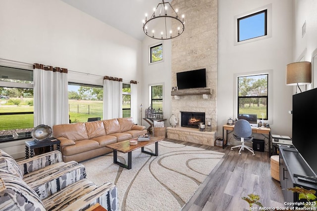 159 Inspiration, Fredericksburg, TX 78624 - living room with high vaulted ceiling, a chandelier, healthy amount of natural light, a stone fireplace, and wood finished floors