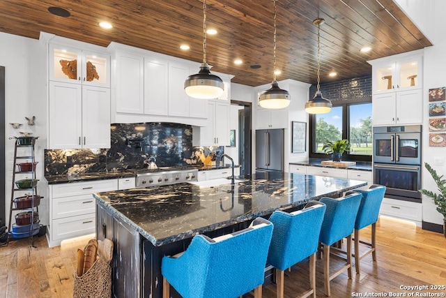 159 Inspiration, Fredericksburg, TX 78624 - kitchen featuring appliances with stainless steel finishes, wooden ceiling, light wood-style floors, tasteful backsplash, and glass insert cabinets