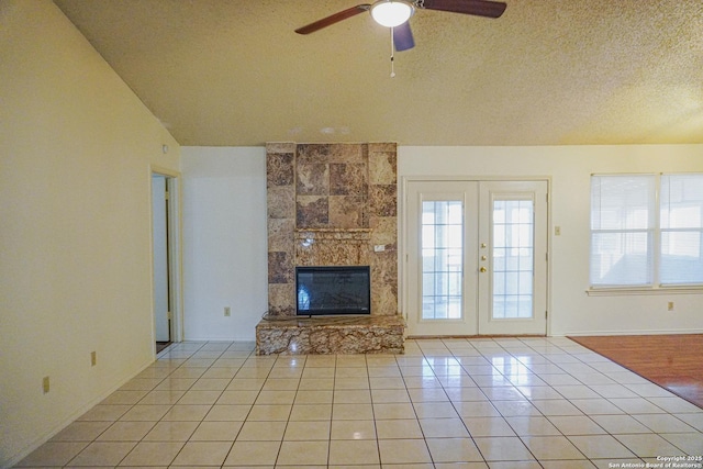 189 Meadowland, Universal City, TX 78148 - unfurnished living room featuring light tile patterned floors, a ceiling fan, vaulted ceiling, a textured ceiling, and a fireplace