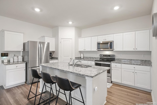 12855 Cygnus, San Antonio, TX 78245 - kitchen featuring stainless steel appliances, a sink, a kitchen breakfast bar, white cabinets, and light wood-style flooring