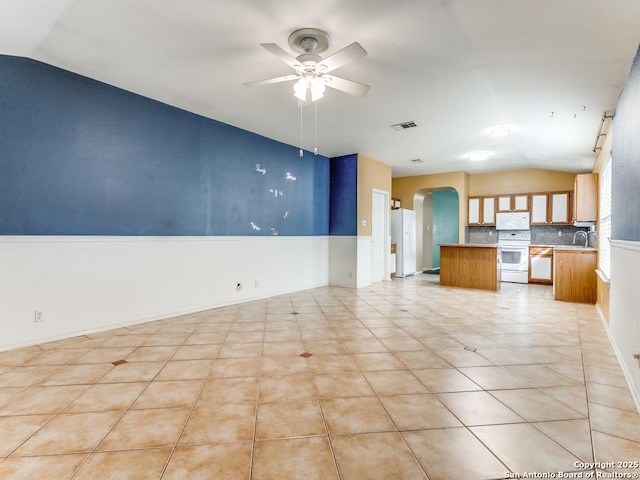 14342 Markham Ln, San Antonio, TX 78247 - unfurnished living room with lofted ceiling, ceiling fan, arched walkways, light tile patterned flooring, and a sink