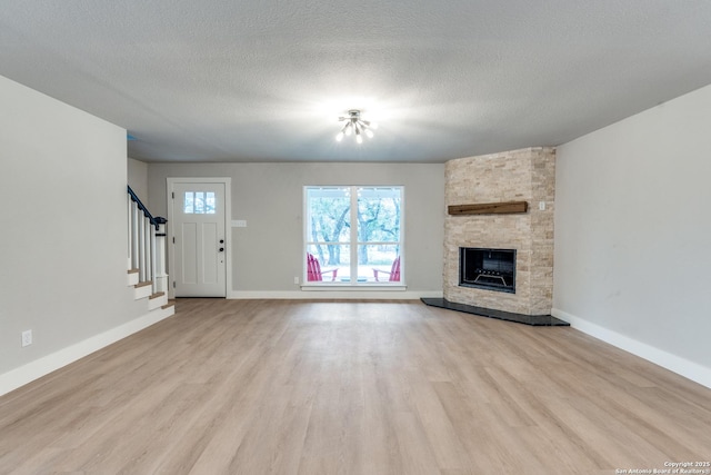 1071 Diamondhead Dr, Canyon Lake, TX 78133 - unfurnished living room featuring light wood-style floors, stairs, a fireplace, baseboards, and a textured ceiling