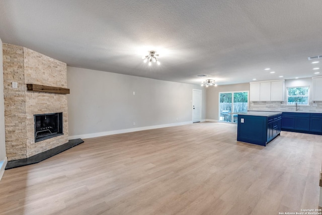 1071 Diamondhead Dr, Canyon Lake, TX 78133 - unfurnished living room featuring light wood-type flooring, a fireplace, baseboards, a textured ceiling, and recessed lighting