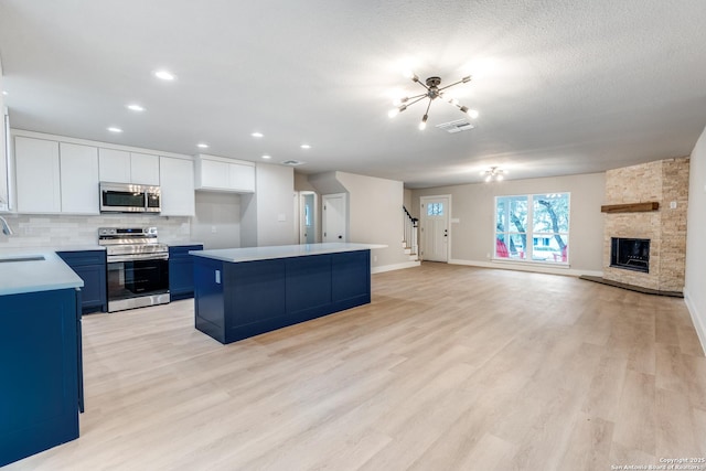 1071 Diamondhead Dr, Canyon Lake, TX 78133 - kitchen with stainless steel appliances, a sink, a kitchen island, backsplash, and light countertops