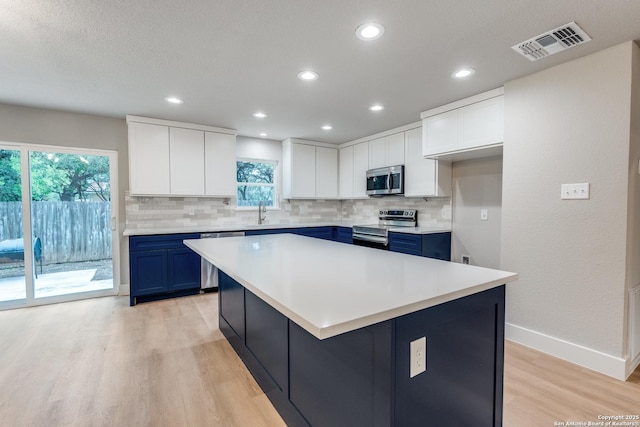 1071 Diamondhead Dr, Canyon Lake, TX 78133 - kitchen featuring appliances with stainless steel finishes, blue cabinetry, light wood-type flooring, decorative backsplash, and recessed lighting