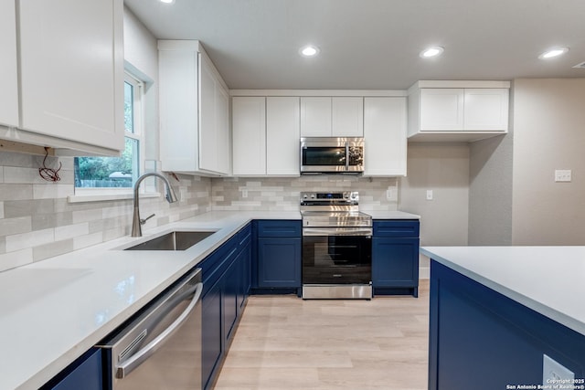 1071 Diamondhead Dr, Canyon Lake, TX 78133 - kitchen featuring stainless steel appliances, a sink, blue cabinets, light wood-style floors, and recessed lighting