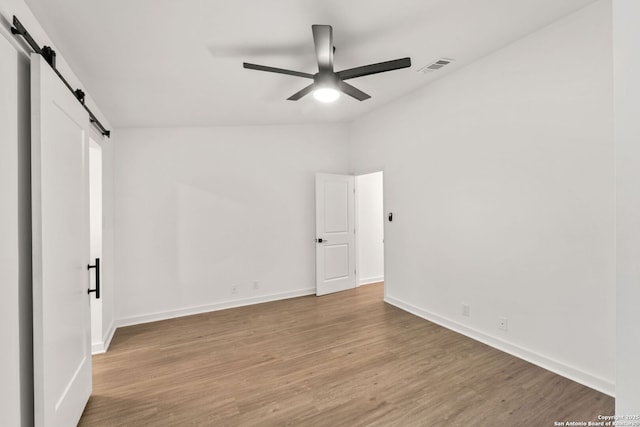 2718 Old Field Dr Unit 101, San Antonio, TX 78247 - unfurnished bedroom featuring a barn door, wood finished floors, baseboards, and ceiling fan