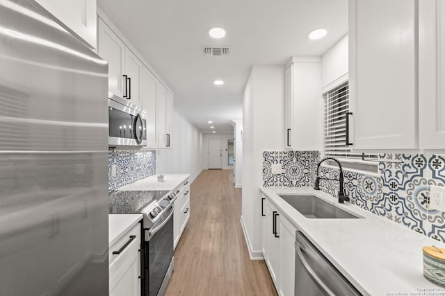 2718 Old Field Dr Unit 101, San Antonio, TX 78247 - kitchen with stainless steel appliances, a sink, light wood-style flooring, white cabinets, and backsplash